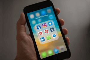 Hand hält Handy mit Social Media Icons